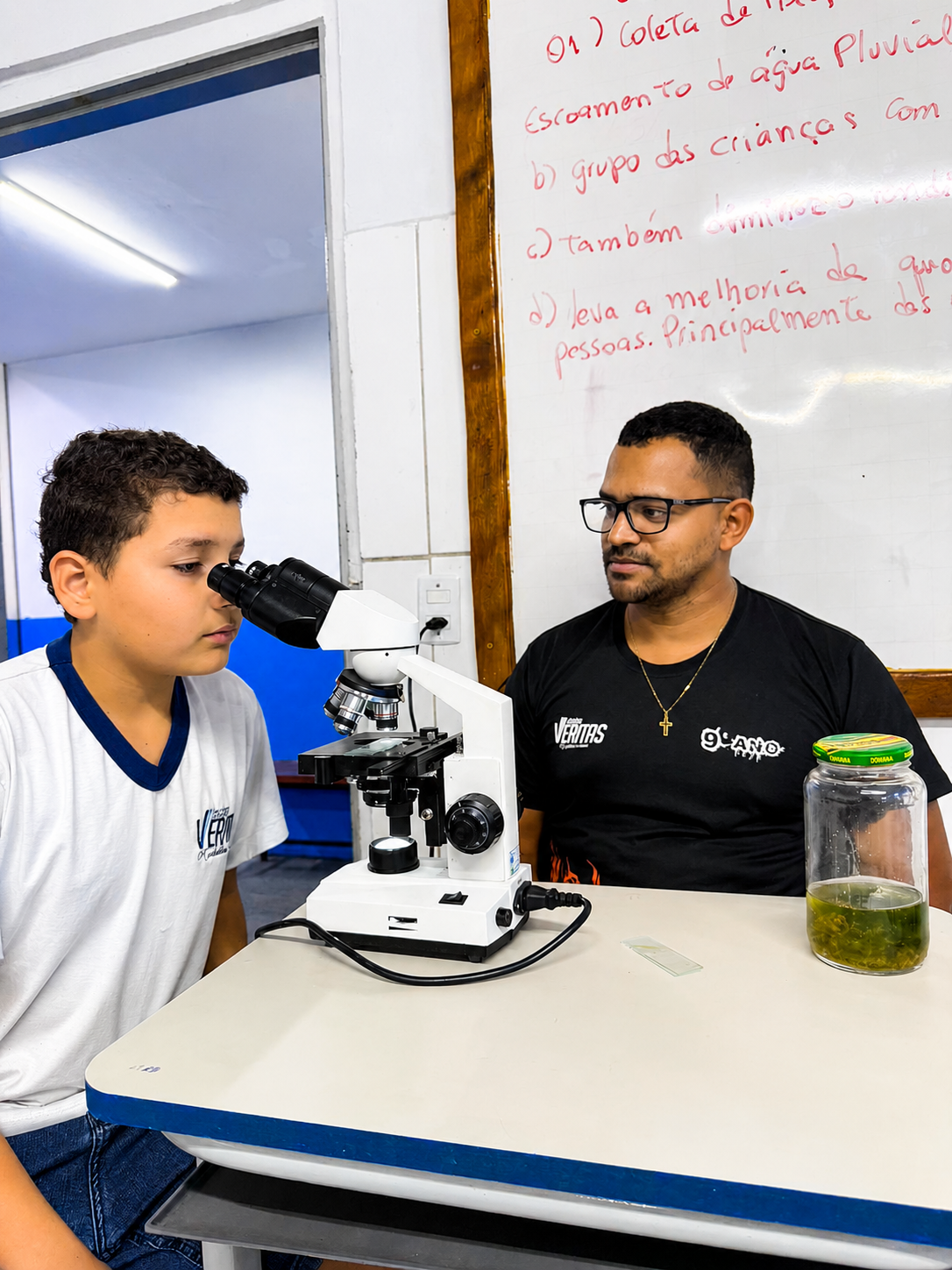 Aluno do Colégio Veritas observando lâmina no microscópio durante aula de ciências